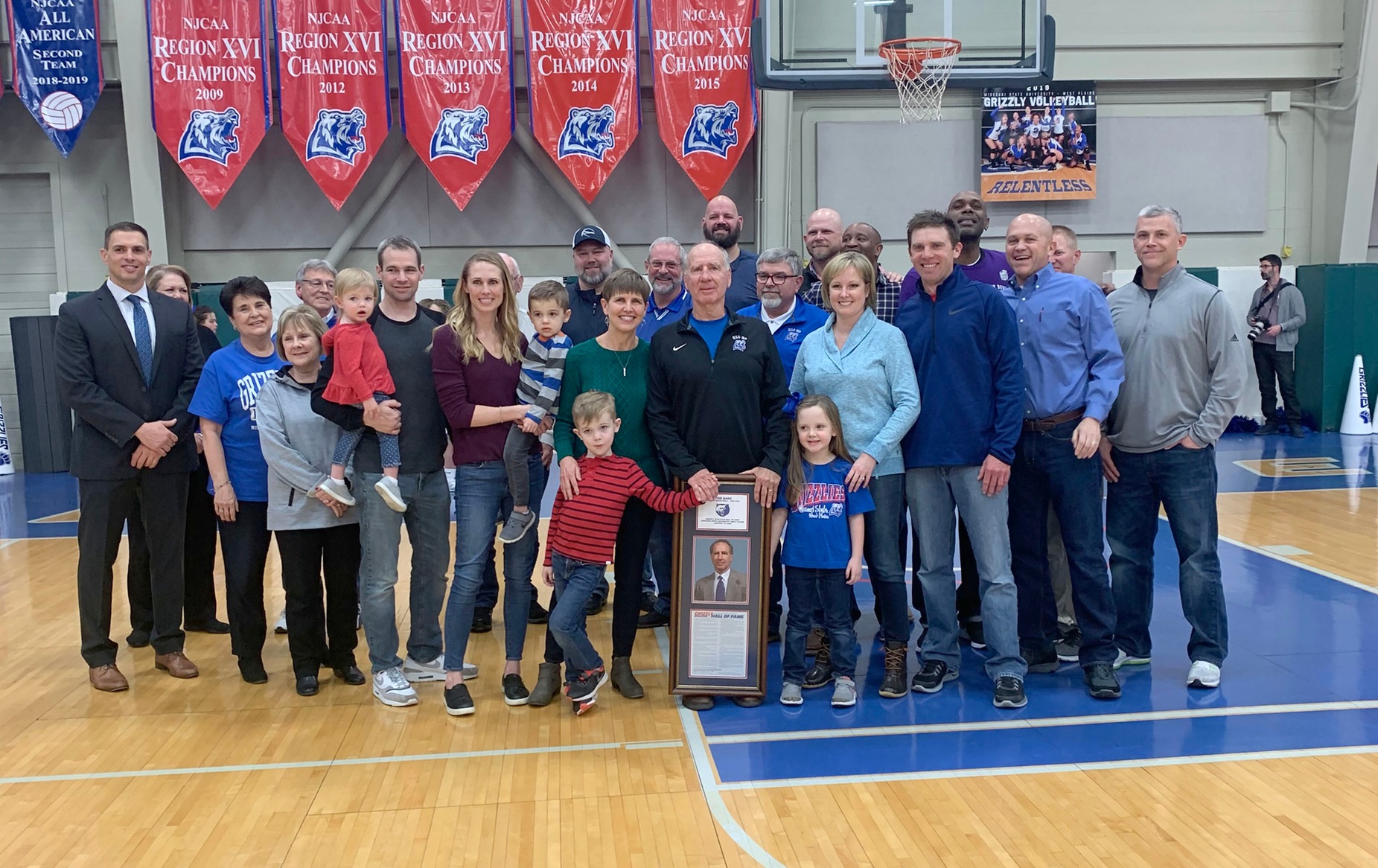 Former Grizzly Basketball Head Coach Tom Barr was inducted into the Grizzly Athletics Hall of Fame Jan. 18 during halftime of the Grizzly Basketball game against Three Rivers College. Celebrating on the court with Barr were, in no particular order, his wife, Kathy, son and daughter-in-law Jared and Leslie Barr; daughter and son-in-law Kerensa and Luke Cassis; grandchildren Mia Barr and Leo, Jett and Chaney Cassis; current Grizzly Basketball Head Coach Chris Popp; Grizzly Booster Club members Carolyn Smith, Donna Frey, Ron Shemwell, John Williams, Russ Gant, John Kenslow, and Frank Mydler; Missouri State-West Plains Chancellor Shirley Lawler; and Barr’s former Grizzlies Donovan Brown, Jason Robbins, Blake Reese, Anthony Perry, Darren Hinshaw, Chuck Campbell, Eric Judd and Daniel Naranich. (Missouri State-West Plains Photo)