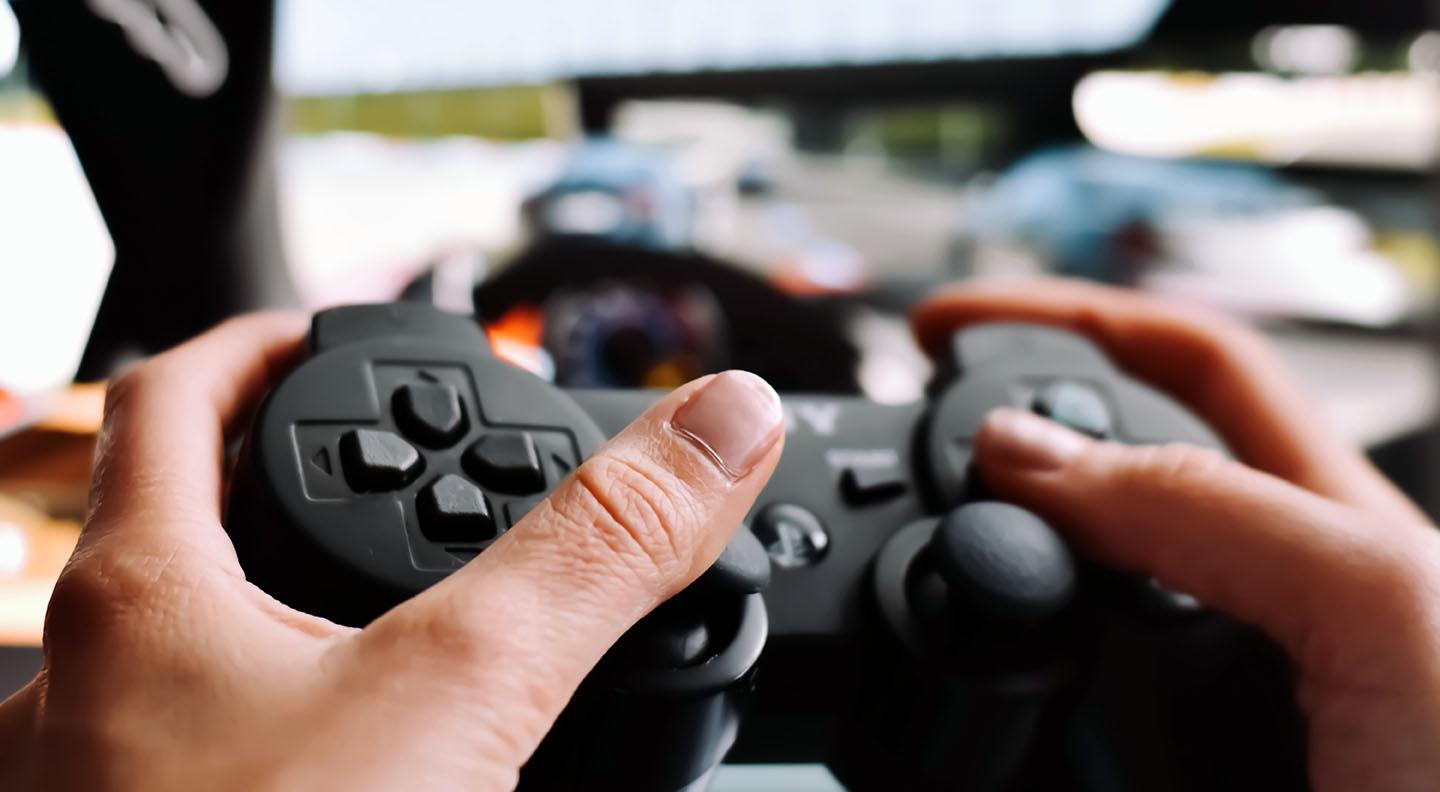 A video game player's hands holding a controller with a screen in the background.