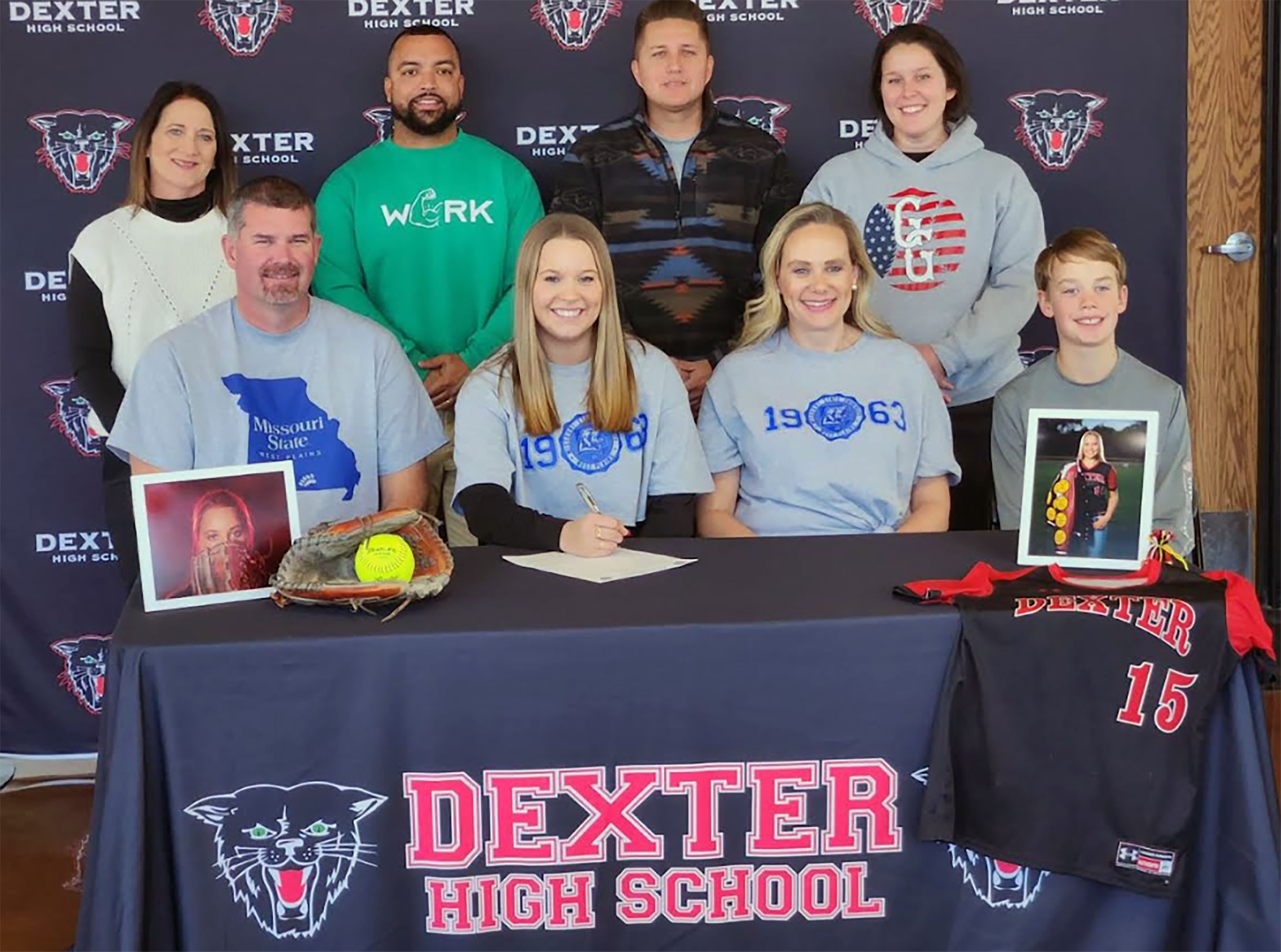 Amelia Jenkins, seated second from left, recently signed a national letter of intent to play for the Grizzly Softball team beginning in fall 2024. With Jenkins above are her father Erik Jenkins, mother Christina Jenkins, brother Drake Jenkins, and her Dexter High School coaches Starla Pulley, Tony Turner, Adam Neal and Chelsea Hoggard. (Photo provided)